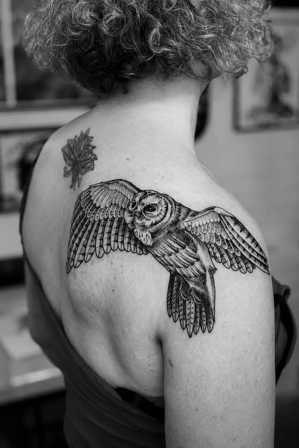Owl in flight tattooed across a shoulder