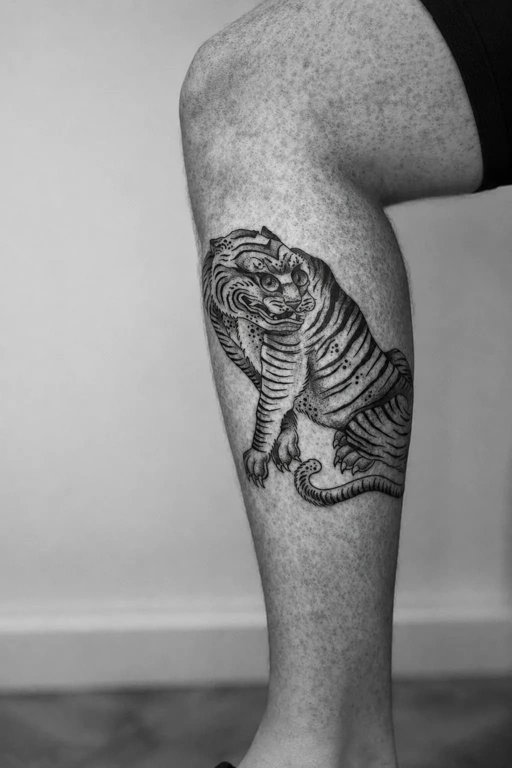 Folk-style tiger tattooed on a calf